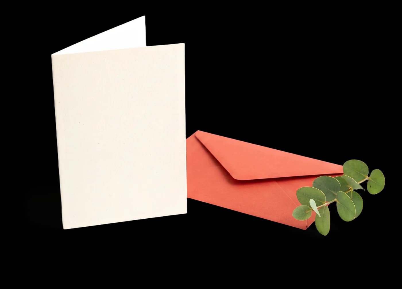 Cartão creme em pé ao lado de um envelope vermelho e folhas de eucalipto